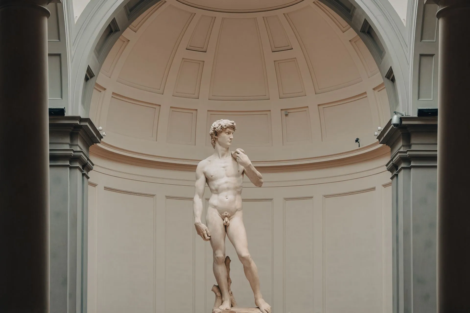Visitors gathered beneath Michelangelo's marble David under the skylit tribune of the Accademia Gallery in Florence