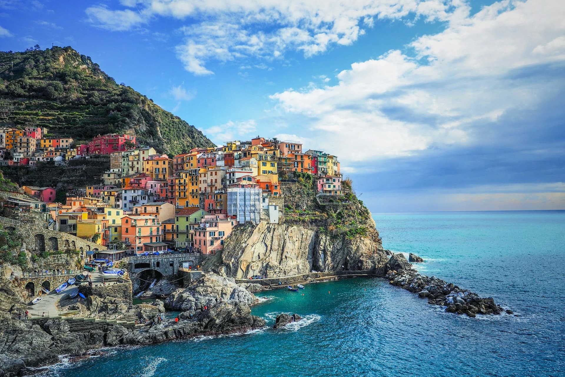 The stacked pastel houses of Manarola above the harbour rocks on the Cinque Terre coast in Liguria, Italy