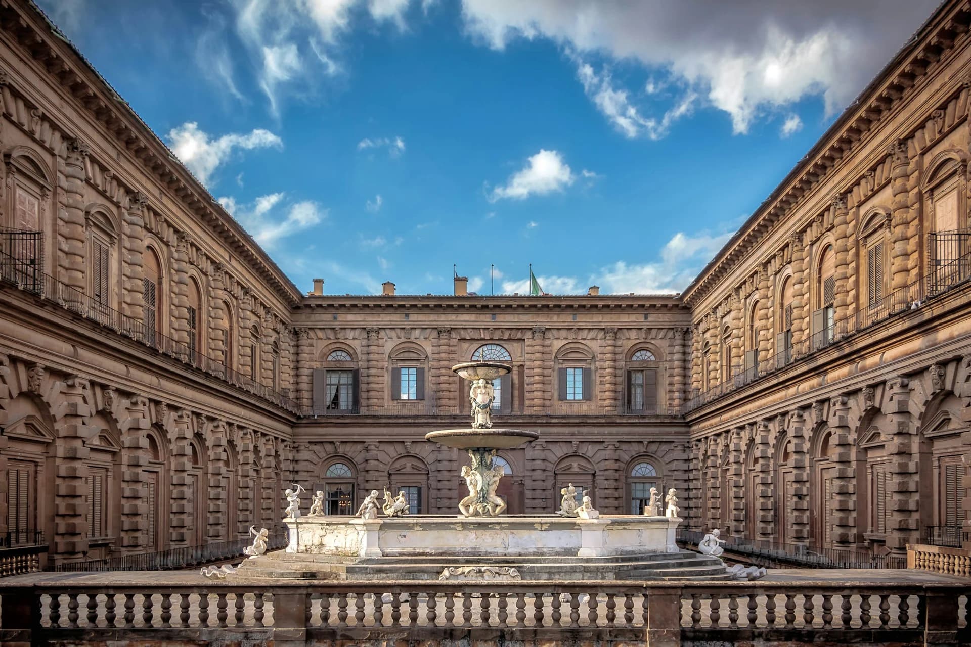 The amphitheatre and terraced lawns of the Boboli Gardens rising behind the stone facade of Palazzo Pitti